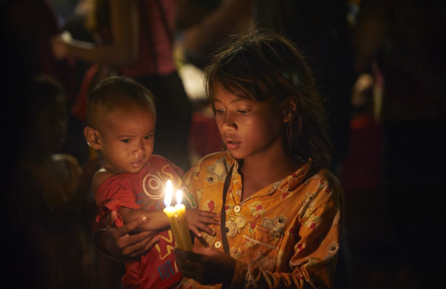 Girl holding small child and candles.