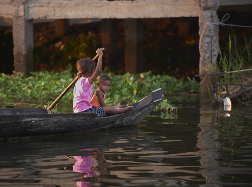 Children rowing boat in floating village in Siem Reap, Cambodia.