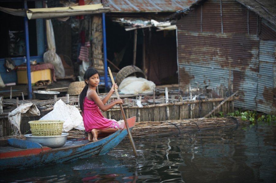 Girl rowing boat in floating village in Siem Reap.