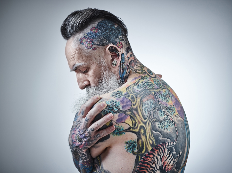Middle aged male showing extensively tattooed body.