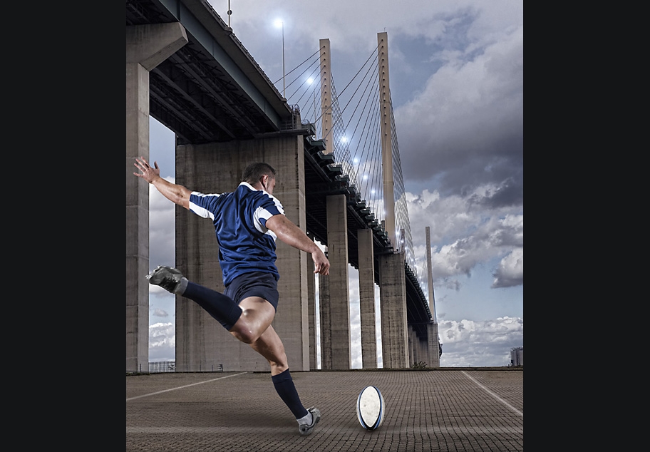 Rugby player kicking ball over bridge