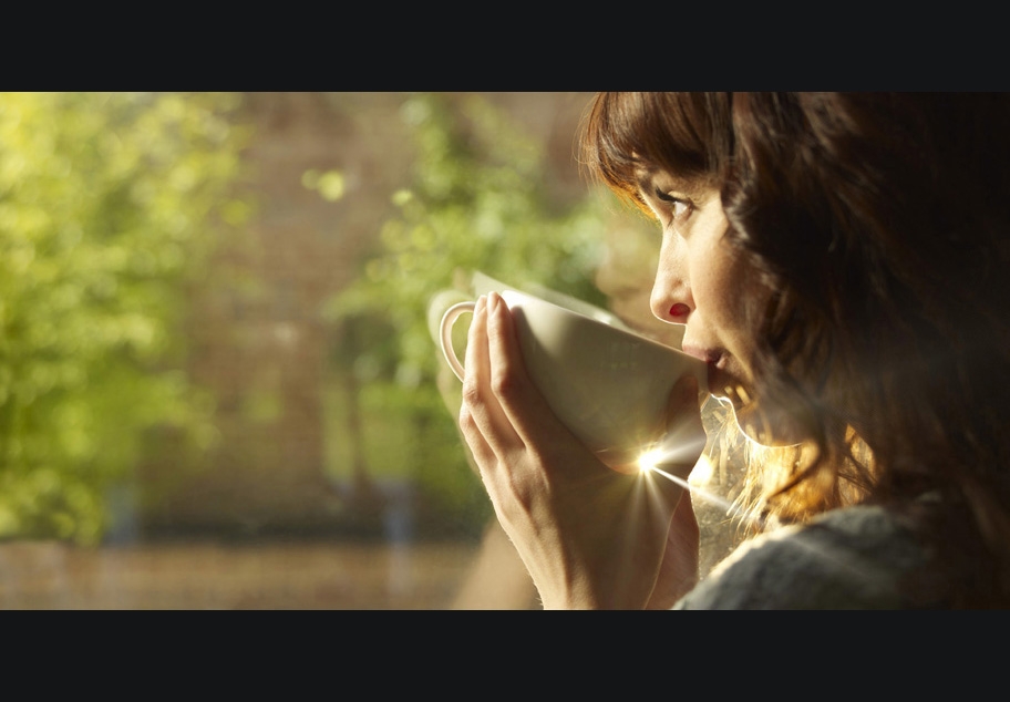 Female drinking coffee looking out of window