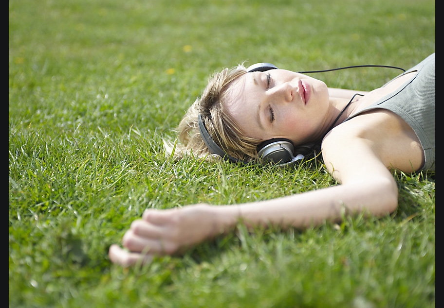 Female laying on grass with headphones on listening to music