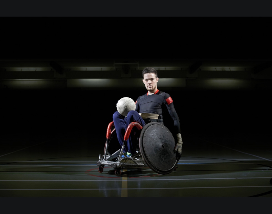 Wheelchair Rugby Player with ball in lap.